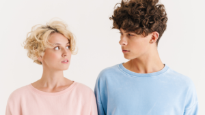 a man and a woman looking at each other wearing pink and blue tops